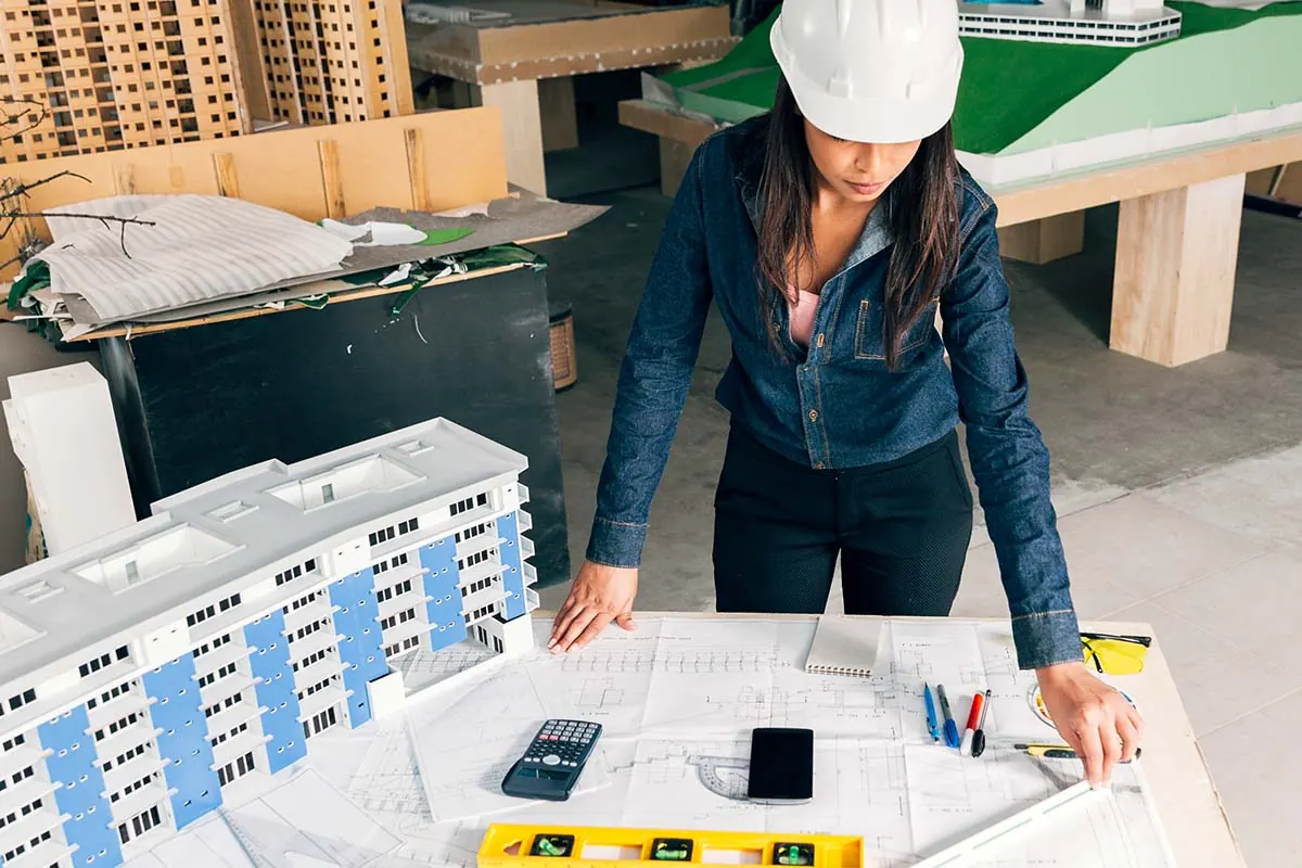 Site manager reviewing building plans next to a scale model