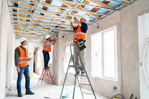 Two tradesmen fitting ceiling joists in a building being renovated